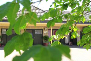 Das Haus der Landküche in Ganderkesee-Stenum, Eingang mit grünen Türen, im Vordergrund Zweige.